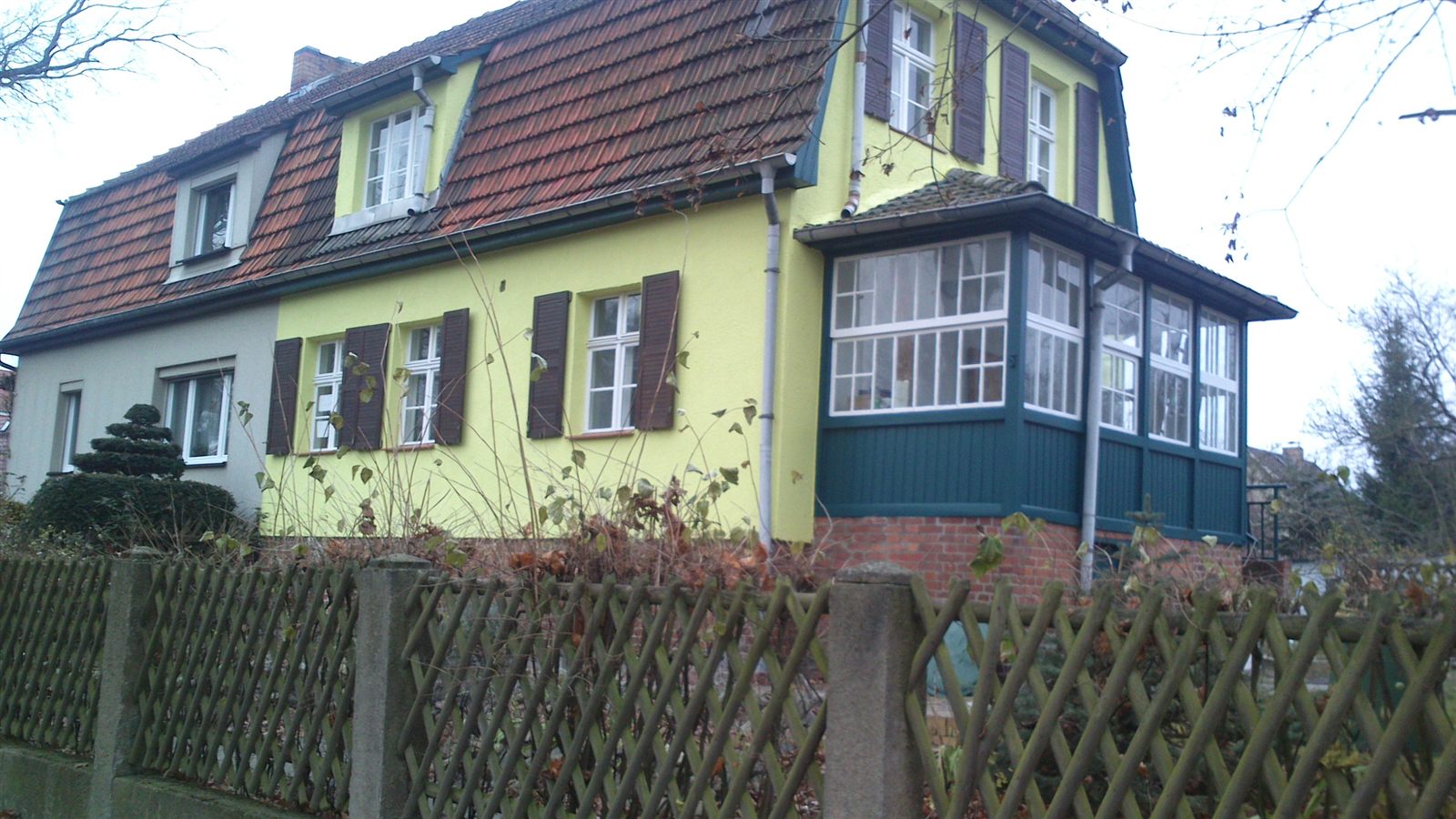 Ansicht der Doppelhaushälfte von Süden mit Mansarddach und Wintergarten